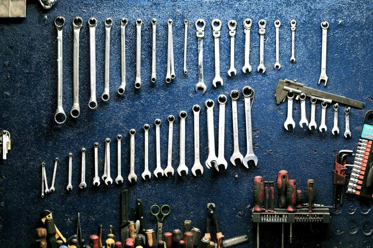 Neatly arranged wrenches and tools on a workshop wall, ideal for mechanics.