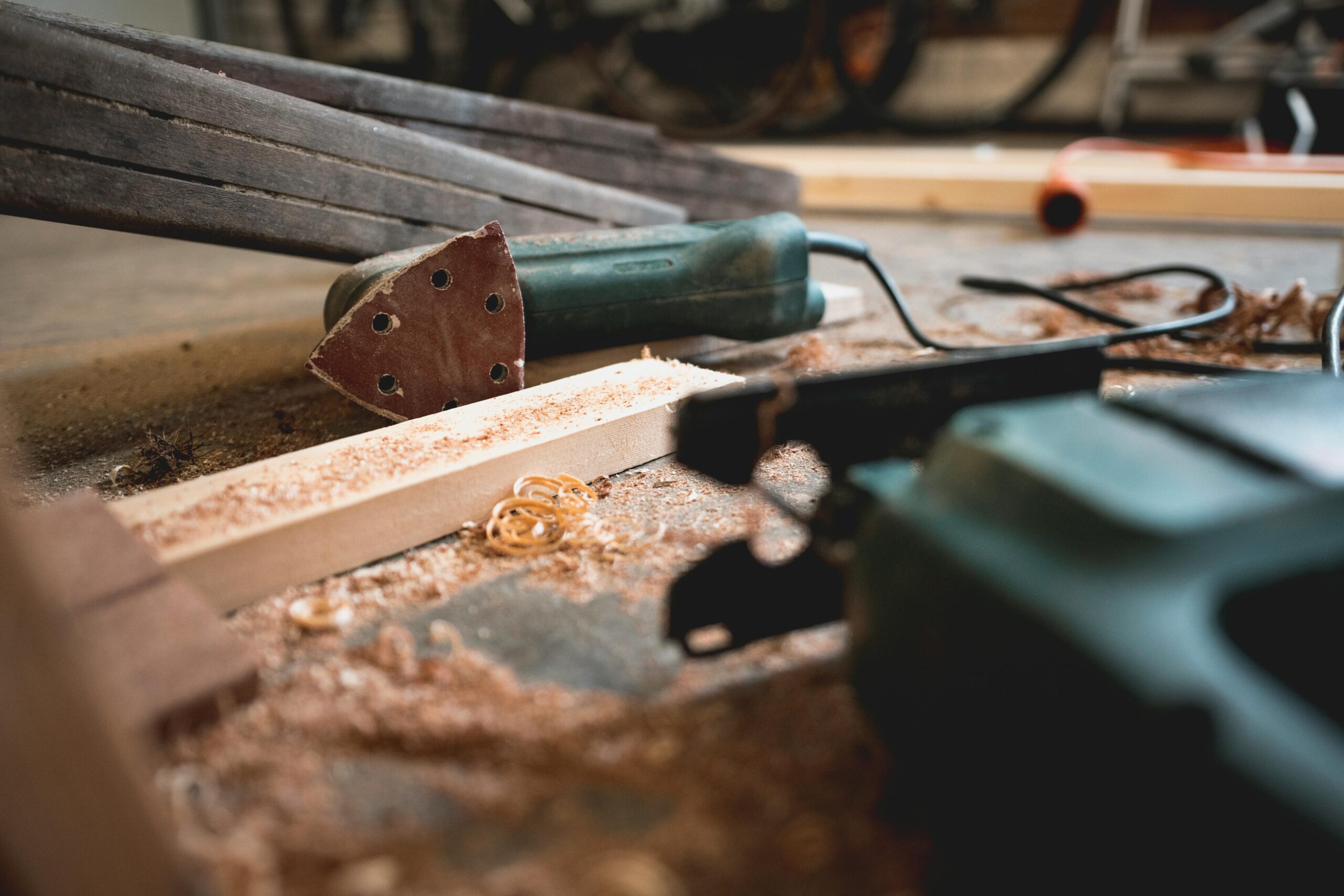 Close-up of various woodworking tools in a workshop, featuring wood shavings and equipment.