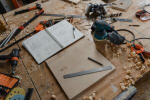 A detailed view of woodworking tools and sketches on a workshop table, showcasing the craft of carpentry.