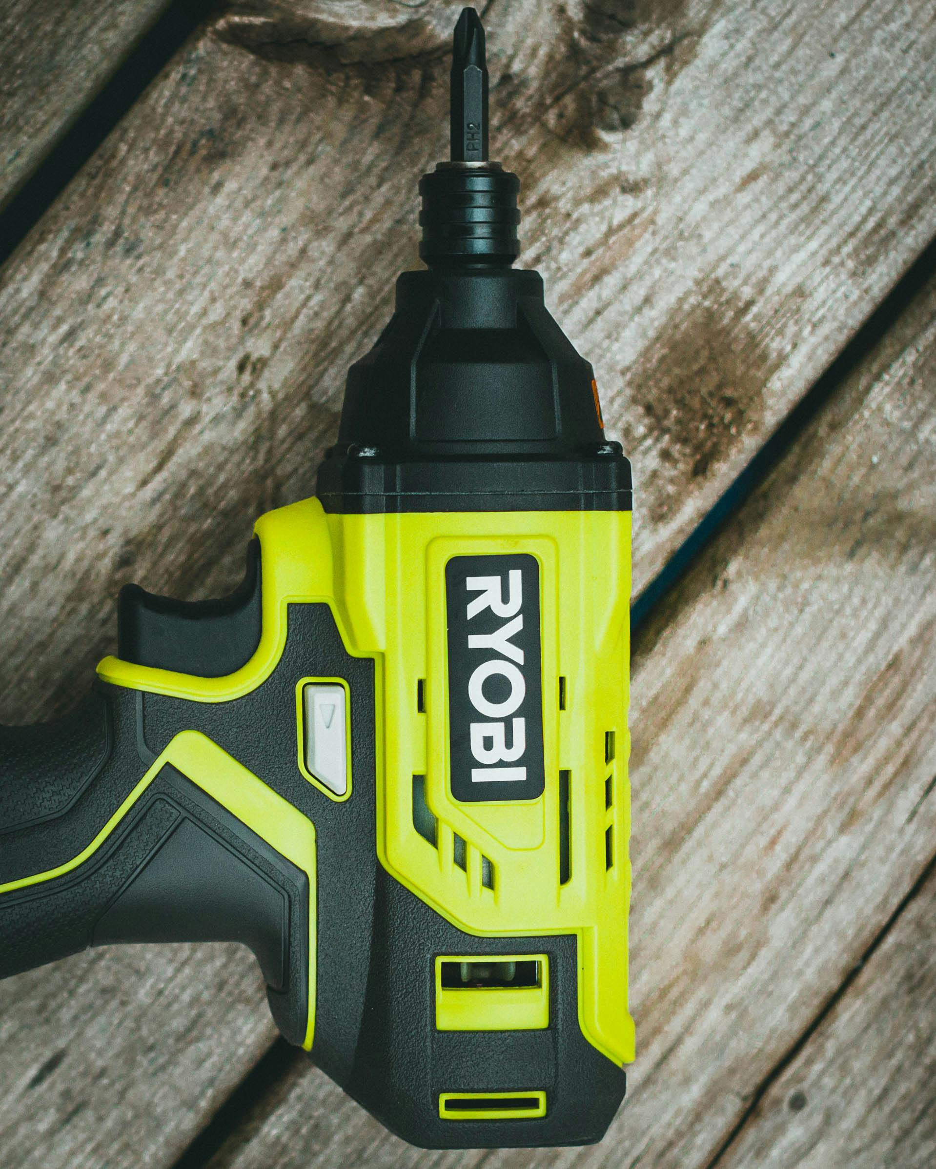 Close-up of a cordless hand drill resting on a rustic wooden surface.